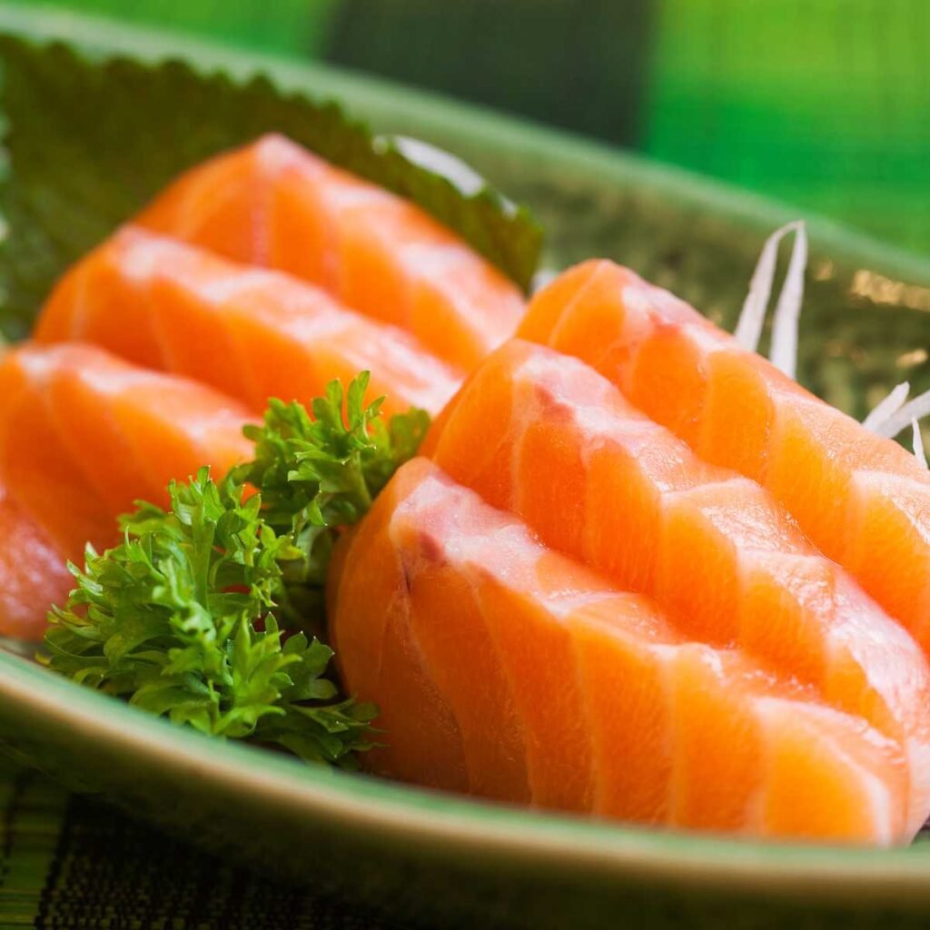 Prato de sashimi de salmão (sake) com fatias frescas e bem cortadas, acompanhado de wasabi e gengibre.