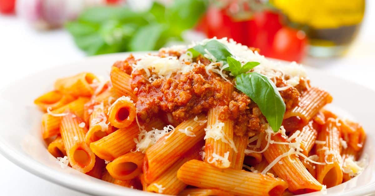 Prato de macarrão penne servido com molho de tomate fresco e manjericão, criando uma refeição leve e saborosa.