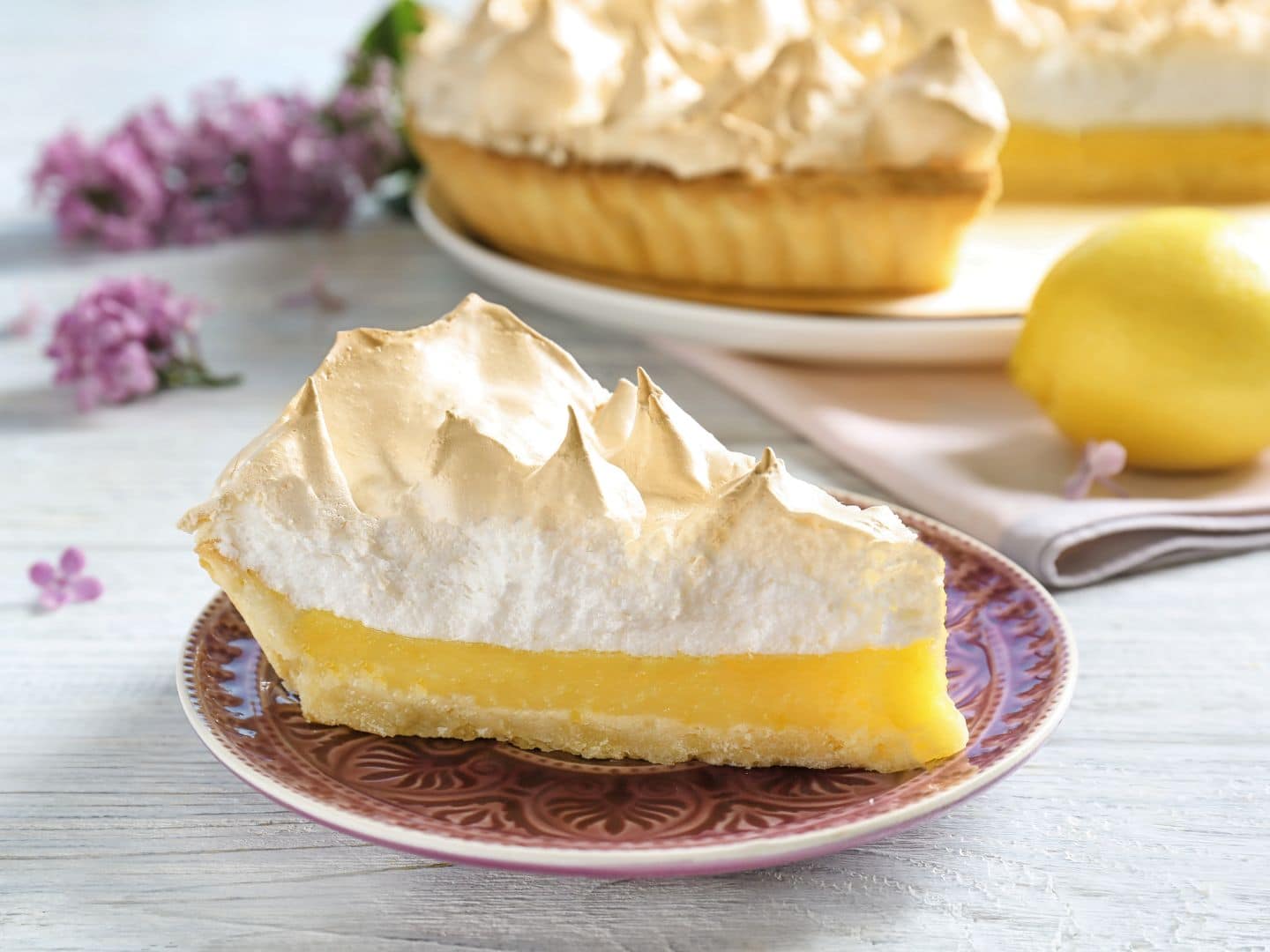 Torta recheada com creme de limão e decorada com raspas de limão.