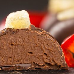 apetitosa trufa de chocolate com pimenta finalizada com cacau em pó e ao fundo pimentas cortadas como decoração.