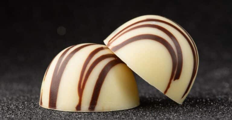 duas trufas de chocolate branco em close em cima de uma mesa.