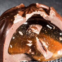 trufa de chocolate belga partida ao meio com recheio gourmet escorrendo.