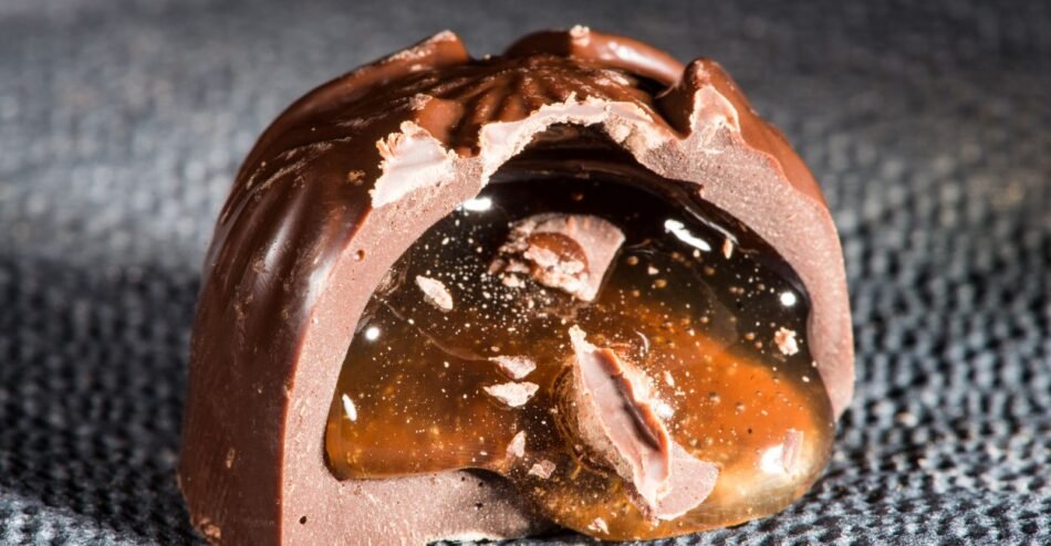trufa de chocolate belga partida ao meio com recheio gourmet escorrendo.