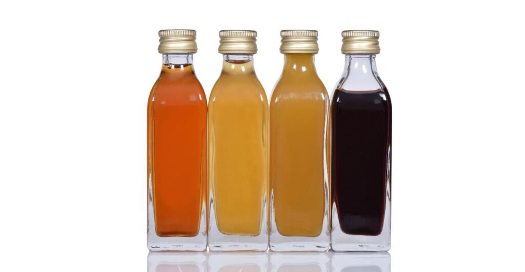 Tipos de vinagres em garrafas de vidro. Vinagre de vinho, vinagre de álcool, vinagre de arros, vinagre de maça.