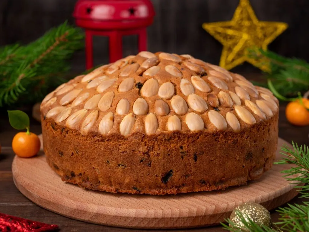 Dundee cake, um bolo tradicional escocês, com frutas secas e nozes visíveis, decorado com amêndoas inteiras e polvilhado com açúcar.