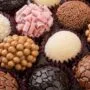 Brigadeiros gourmet em uma bandeja, com diferentes coberturas como chocolate granulado, coco ralado e chocolate picado e outros confeitos.