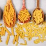 diversos tipos de macarrão dispostos em uma mesa como, espaguete, tortellini, fusili, penne, gravatinha.