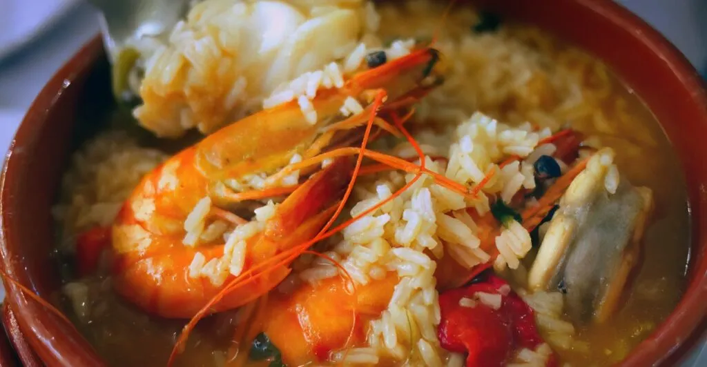 Arroz de marisco cremoso com camarões, mexilhões e coentros frescos, prato típico da culinária portuguesa.