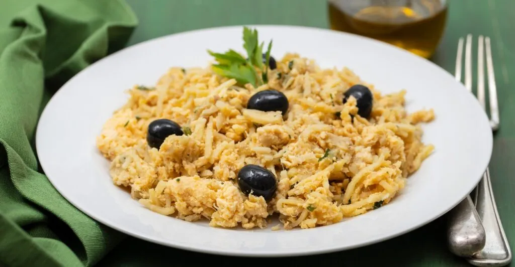 Bacalhau à Brás servido em prato tradicional com batata palha e ovos mexidos, típico da culinária portuguesa.