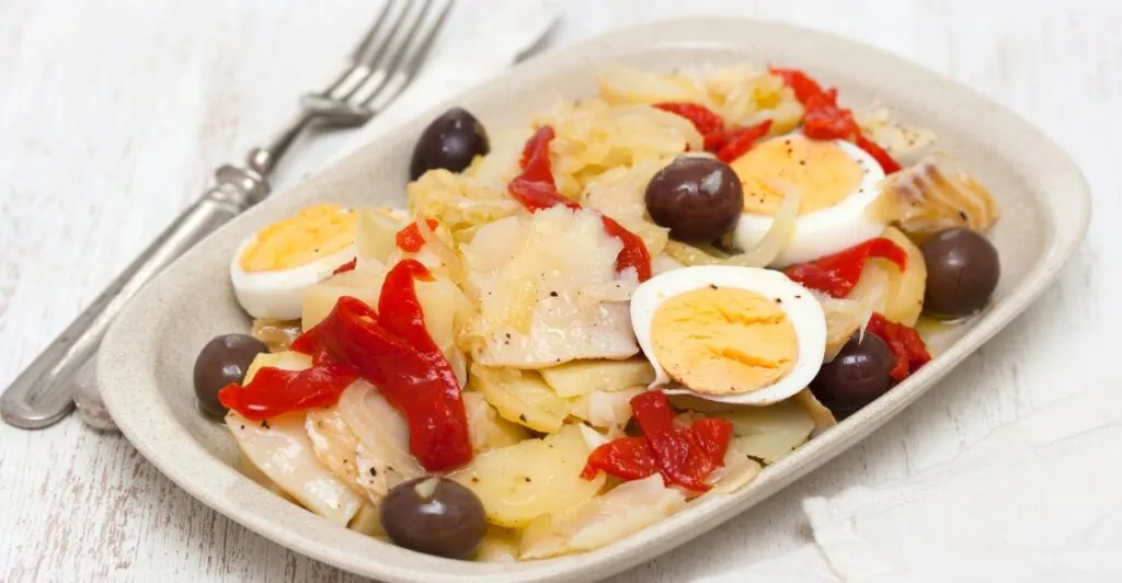Bacalhau à Gomes de Sá com ovos cozidos, azeitonas pretas e batatas, prato clássico da culinária portuguesa.
