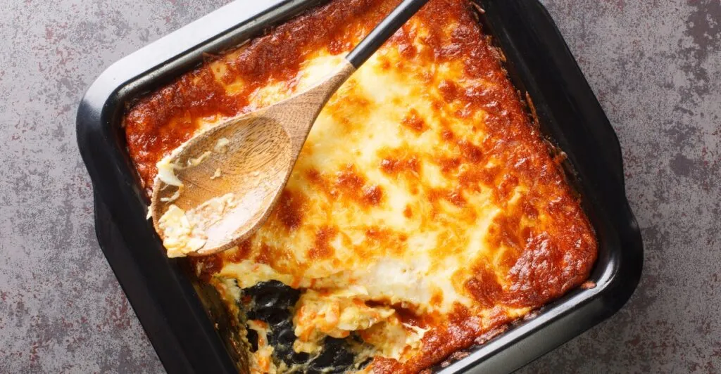 Bacalhau espiritual servido gratinado, com creme branco e cenoura ralada, prato da culinária portuguesa.
