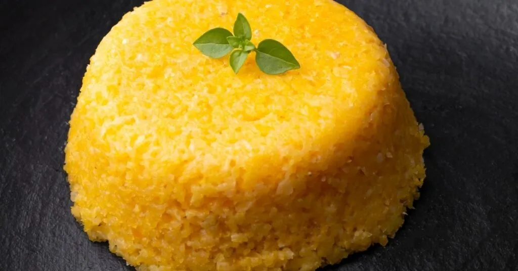 Prato de cuscuz nordestino servido com manteiga, comida de festa junina salgada.