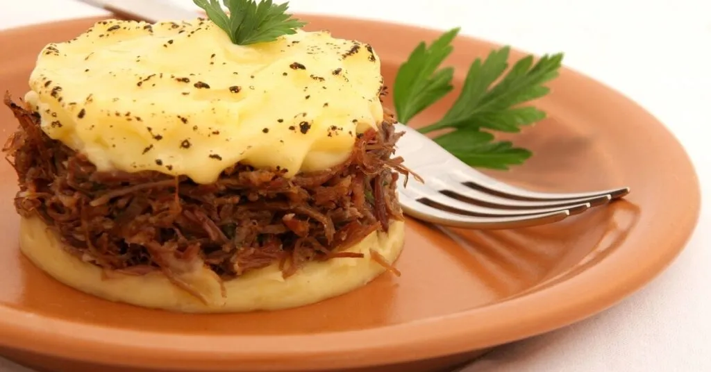 Escondidinho de carne-seca com purê dourado por cima, comida de festa junina salgada.