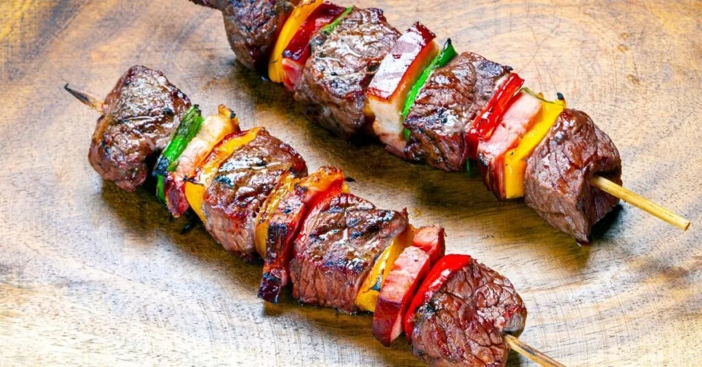 Espetinho de carne grelhada com molho, comida de festa junina salgada.