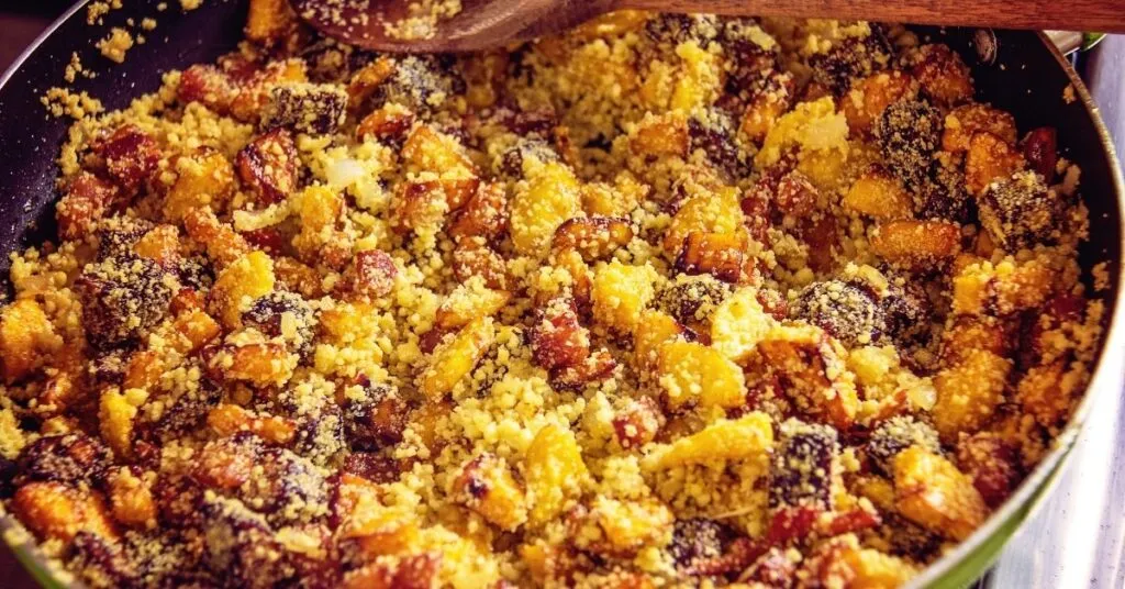 Farofa caipira com bacon, calabresa e legumes, servida em travessa rústica, comida de festa junina salgada.