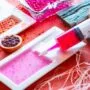 Seringa aplicando líquido colorido em gotas para formar esferas de gastronomia molecular sobre superfície branca.