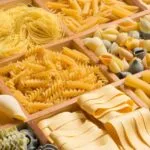 Mesa com vários tipos de macarrão nomes e formatos da massa italiana.